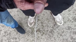 Friend is holding my cock while im peeing on the ground outdoor